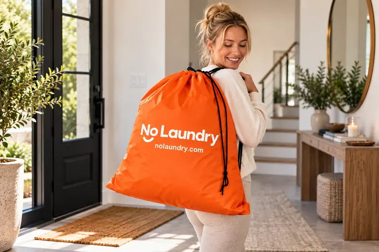 A woman carries an orange NoLaundry bag through her front door