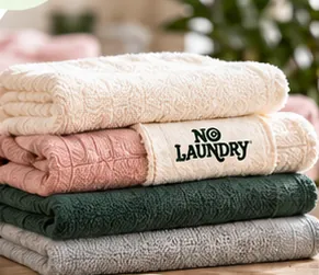 A neat stack of cream, pink, green and grey folded NoLaundry towels